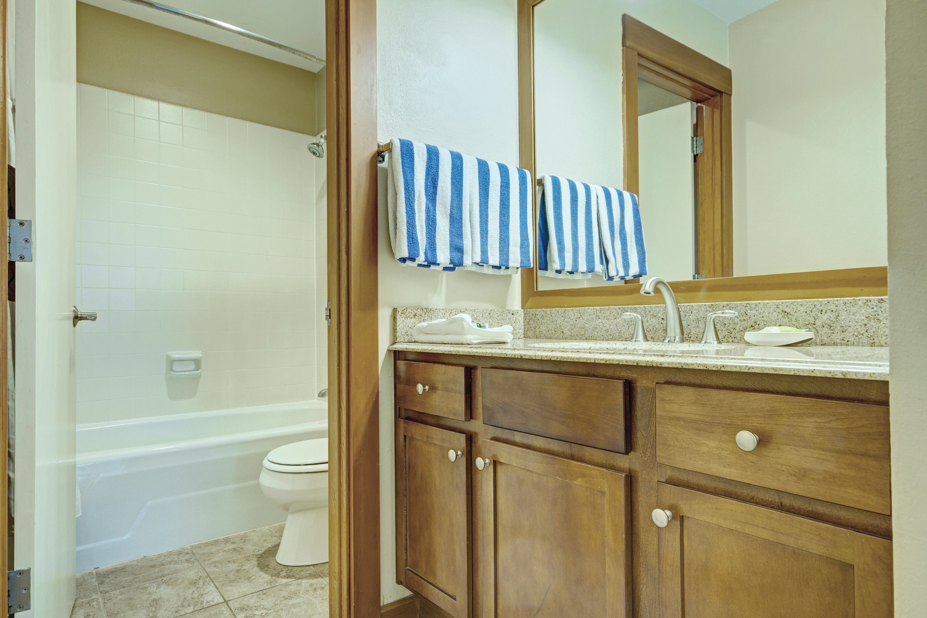 A bathroom with wooden cabinets, a sink, and a mirror.