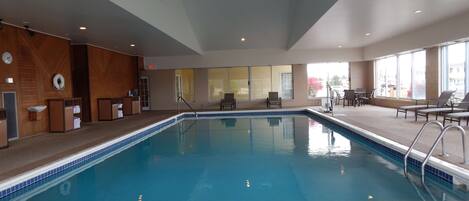 An indoor swimming pool with a 'NO DIVING' sign, lounge chairs, and a view of the outside.