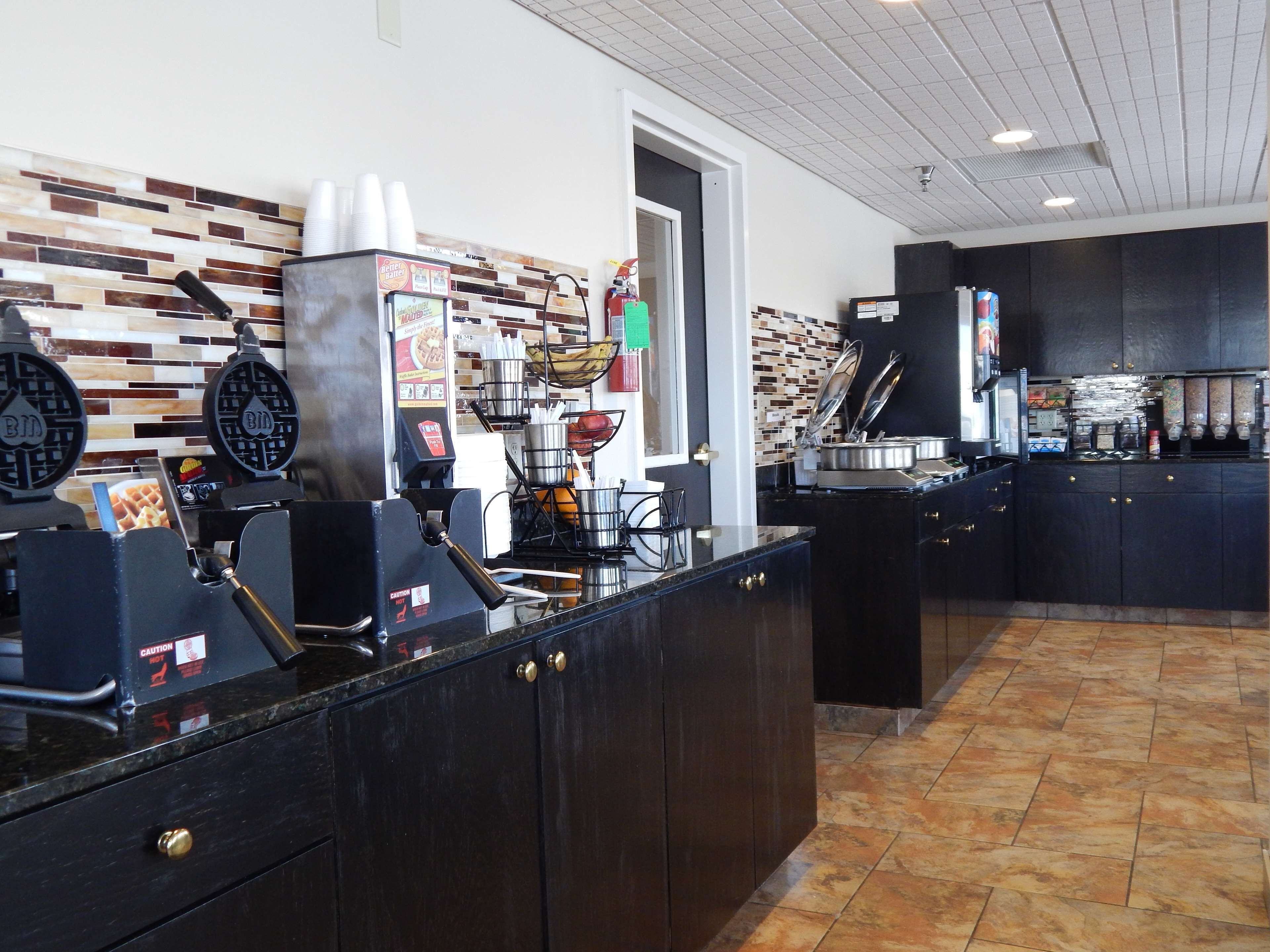 A coffee station with a waffle maker, a coffee machine, and a menu board.