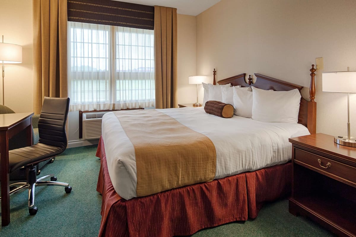A hotel room with a large bed, two bedside tables, a desk, and a chair.