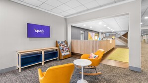 Een moderne lobby met een receptiebalie, een kinderspeelruimte en zitplaatsen.