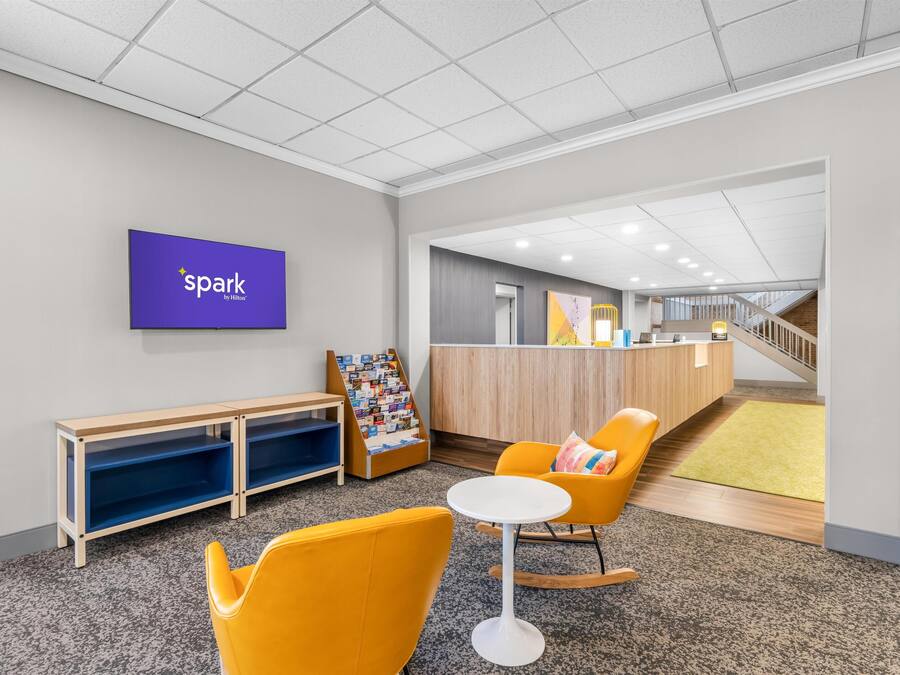 A modern lobby with a reception desk, a children's play area, and seating.