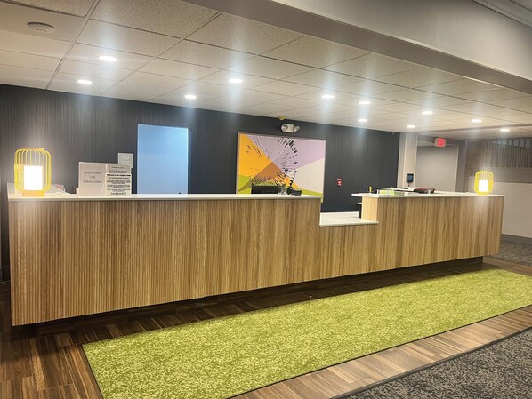A reception desk with a wooden finish, a green carpet, and a wall-mounted sign indicating the pool is closed for renovations.