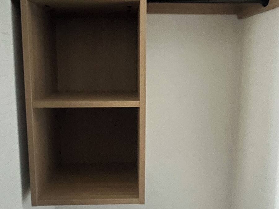 A wooden shelf unit with two compartments and a pull handle.