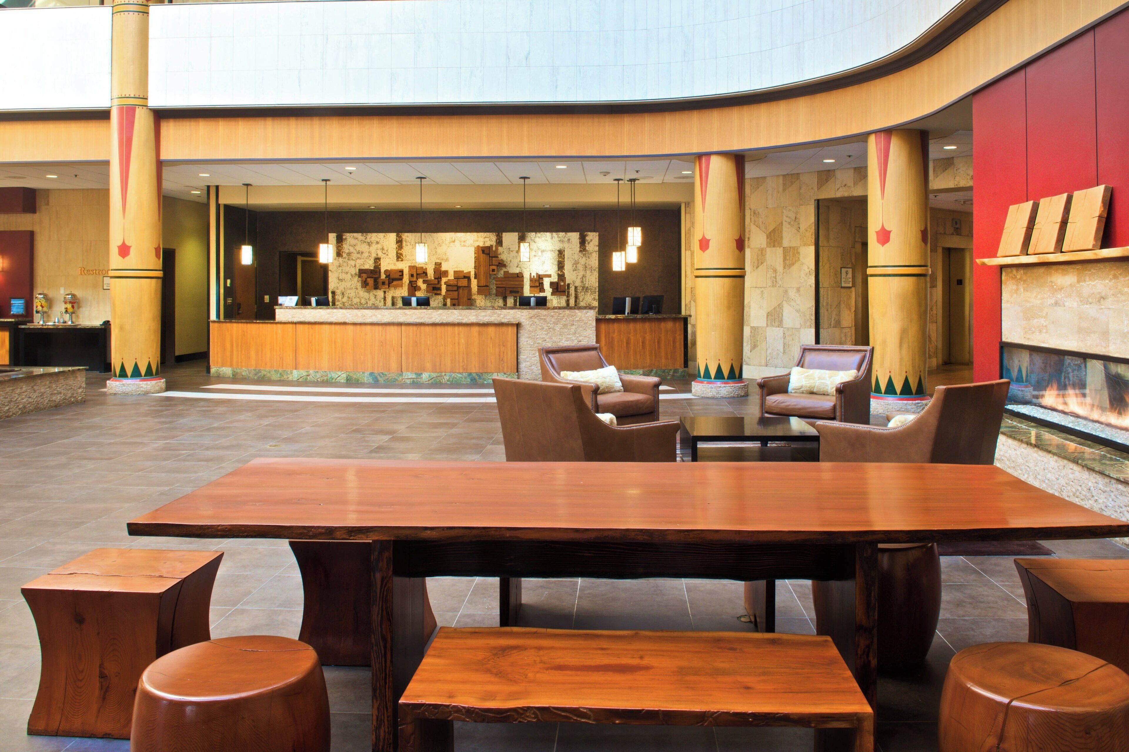 Een ruime lobby met een houten receptiebalie, comfortabele zitplaatsen en een open haard.