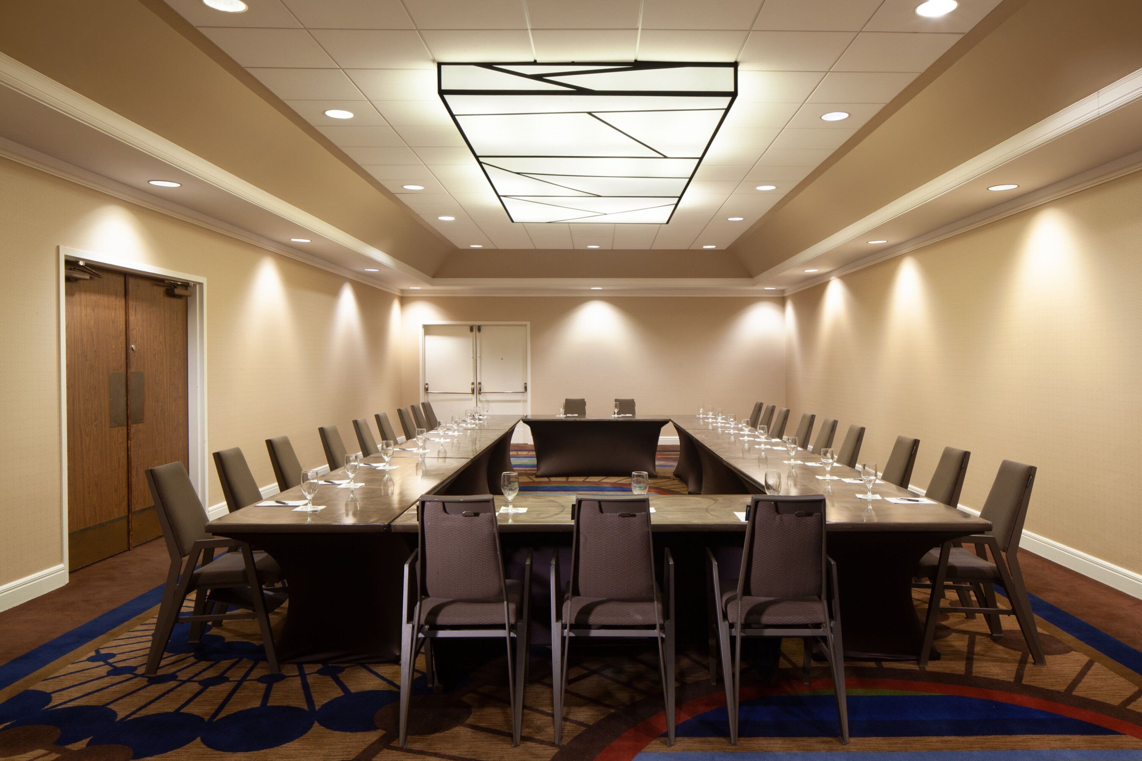 A conference room with a long table, chairs, and a carpeted floor.