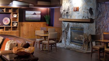 Un salon confortable avec une cheminée en pierre, des meubles en bois, un téléviseur fixé au mur et un mur décoratif.