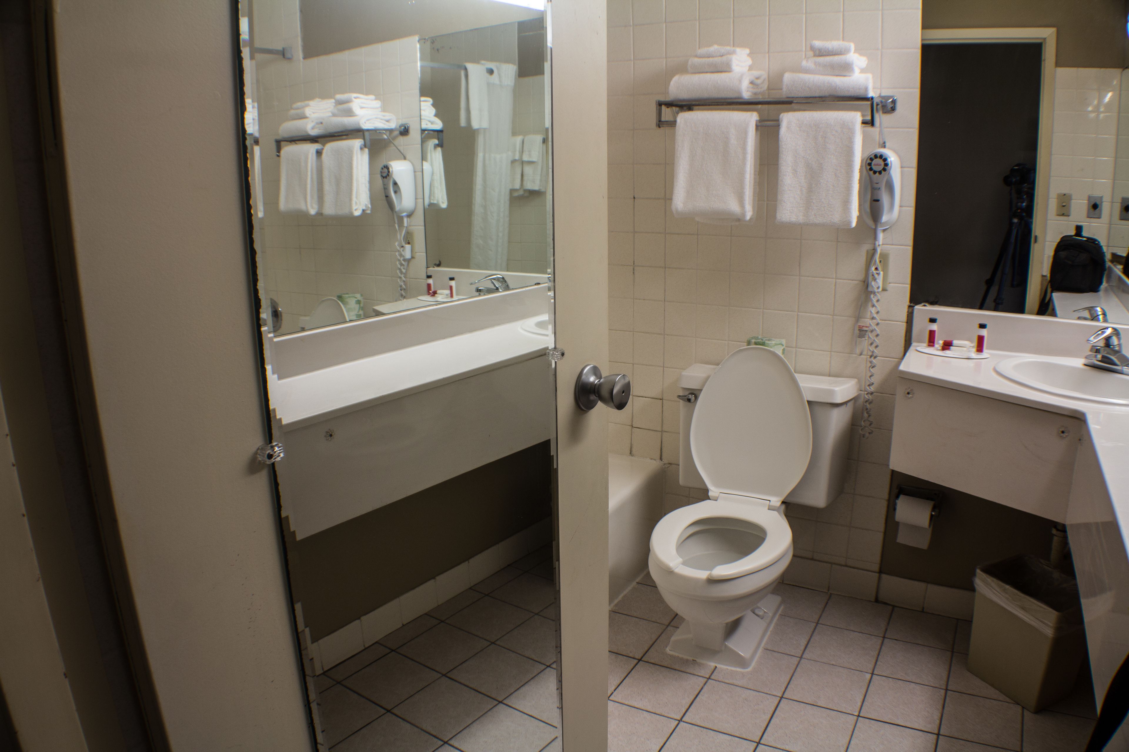 A standard hotel bathroom with a toilet, sink, and mirror.