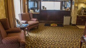 A hotel room with patterned carpet, a bar area, and two armchairs. - Econo Lodge Erie near Casino (Erie)