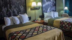 A hotel room with two beds, each with a patterned bedspread, a nightstand with a lamp, and a painting on the wall. - Econo Lodge Erie near Casino (Erie)