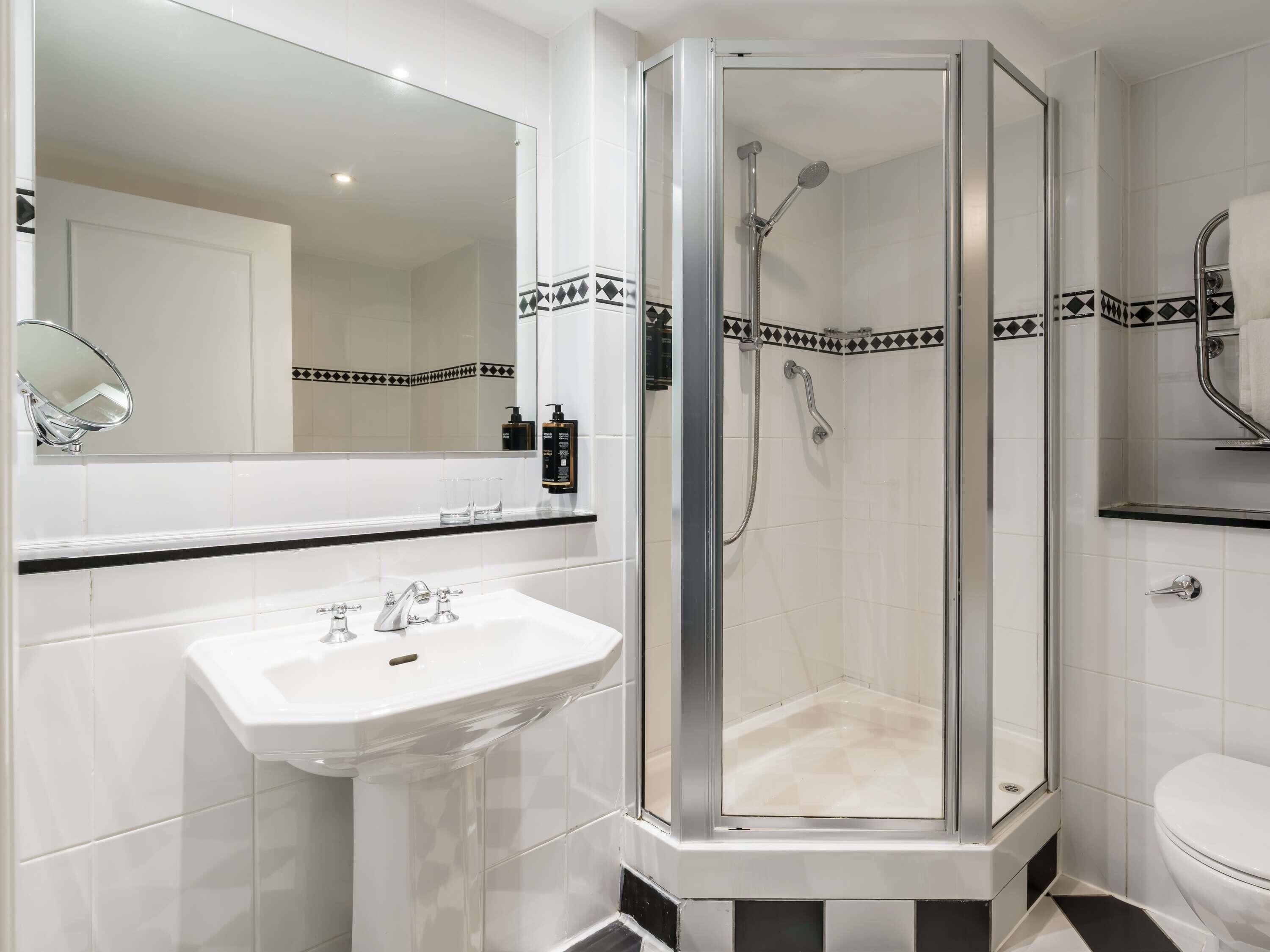 Une salle de bain moderne avec une douche à parois de verre, un lavabo blanc et un grand miroir.