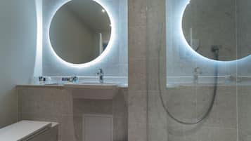 Un baño moderno con un espejo redondo, un lavabo y una ducha.