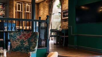 Interior de restaurante con pared de piedra, zona de bar y una disposición de mesas con una mesa redonda y sillas.
