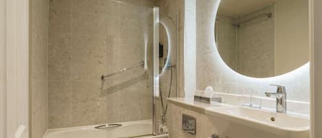 Un baño moderno con bañera, inodoro y un espejo grande.