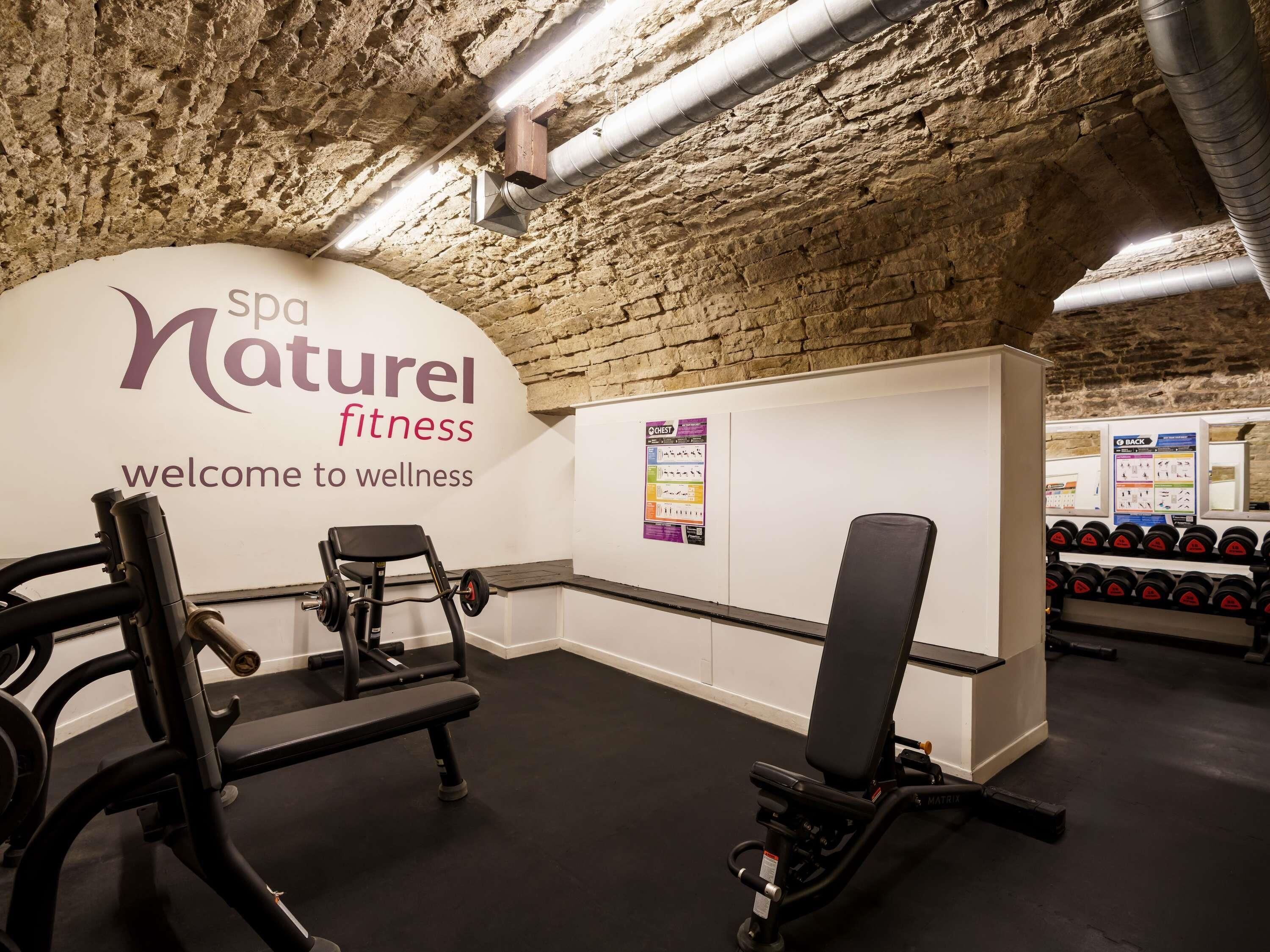 Ein Fitnesscenter mit Spa-Bereich, das mit einer Steinsäule, Trainingsgeräten und einem Empfangsschild ausgestattet ist.