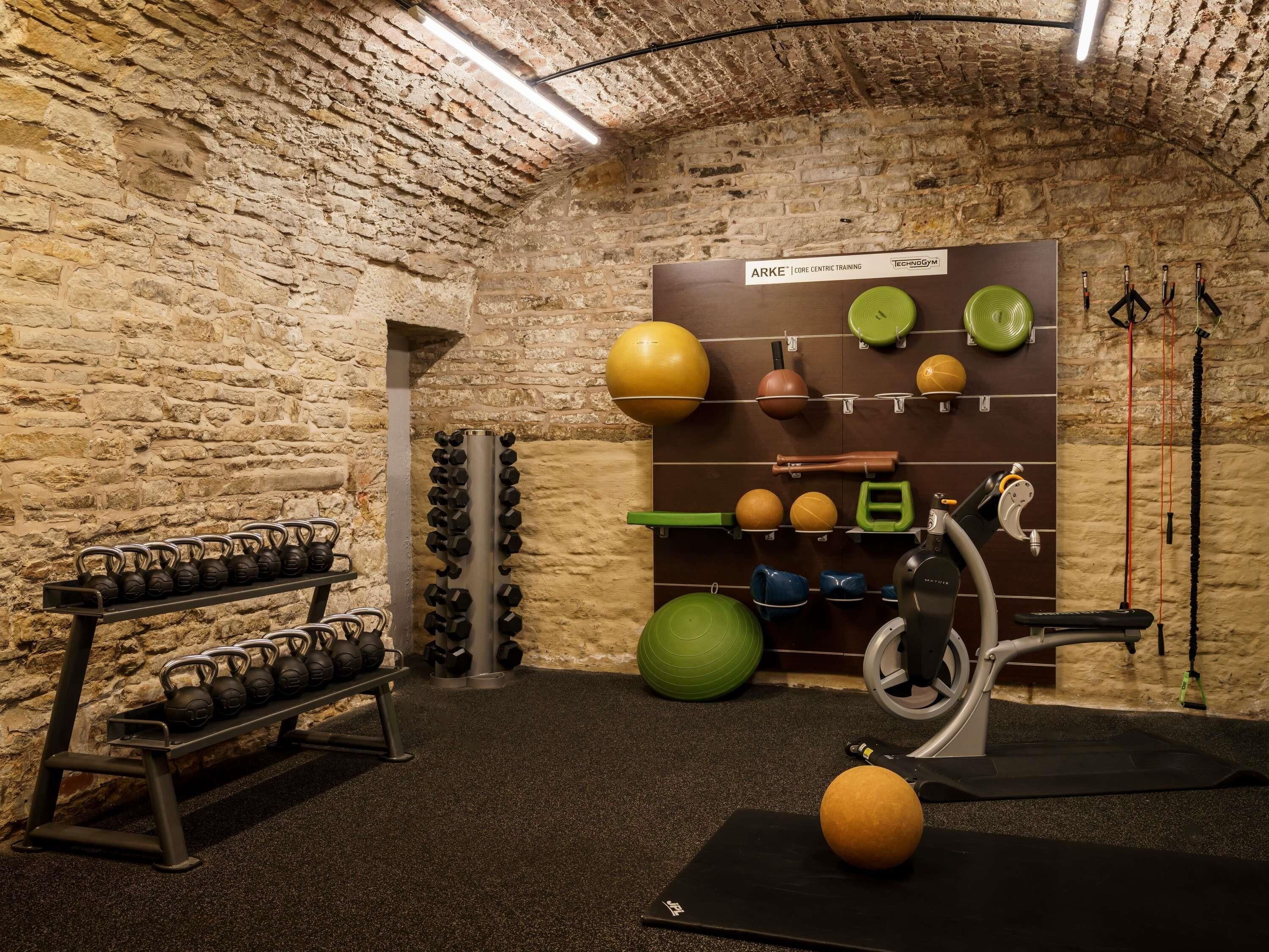 Een sportschool met kettlebells, medicine ballen en een hometrainer.