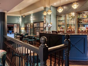 A bar area with a counter, seating, and a view of the dining area.