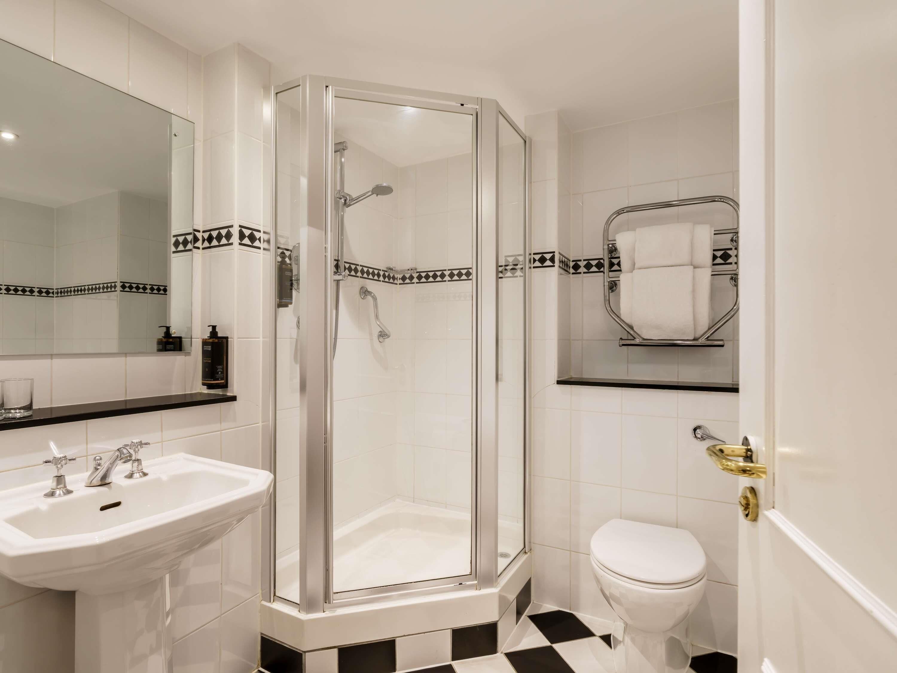 A bathroom with a glass-enclosed shower, a white sink, and a toilet.