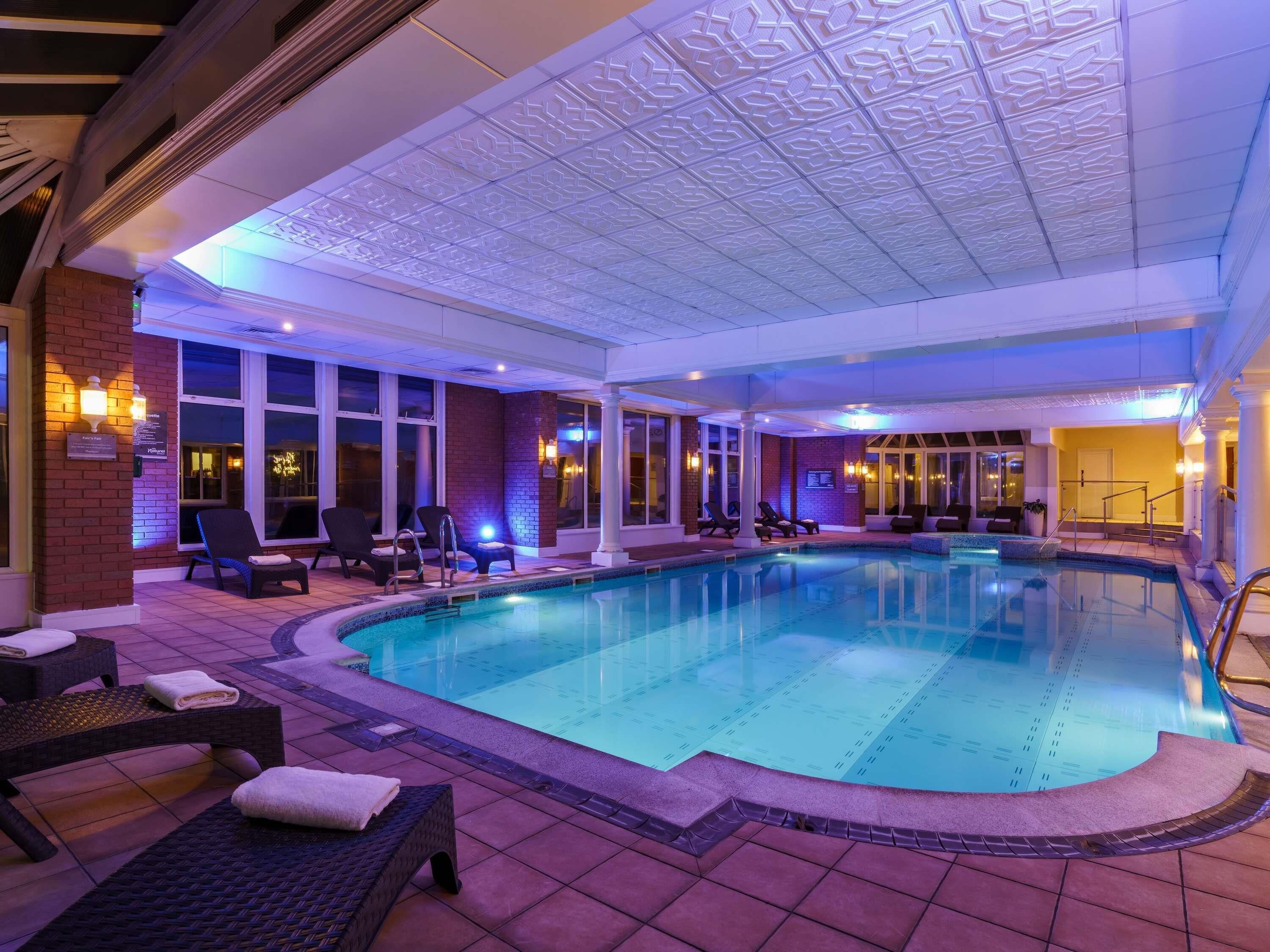 A pool area with lounge chairs and a ceiling with intricate patterns.
