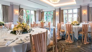 Ein Bankettsaal mit runden Tischen, weißen Tischdecken und floralen Tischarrangements.