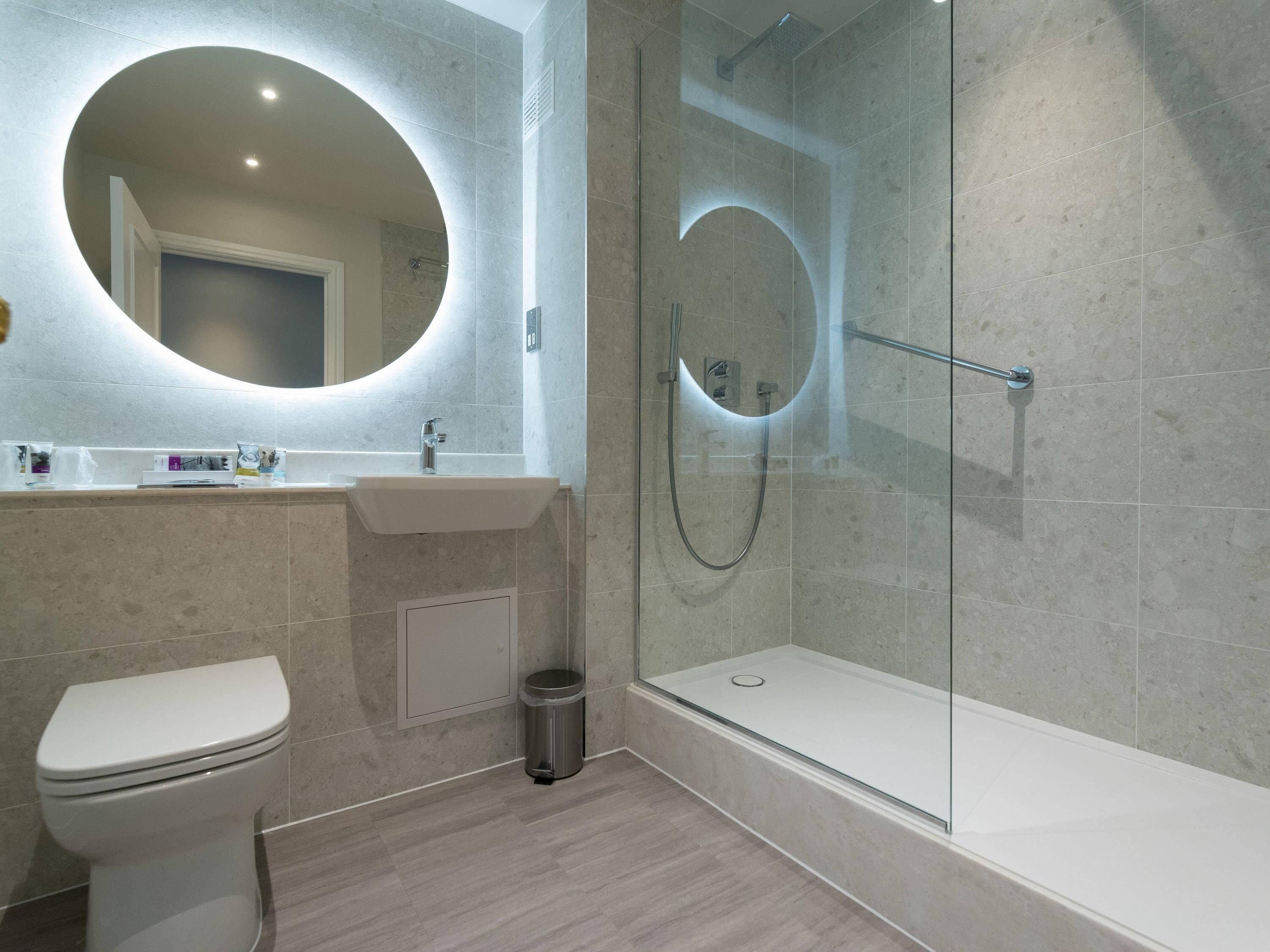 A modern bathroom with a toilet, sink, and glass-enclosed shower.