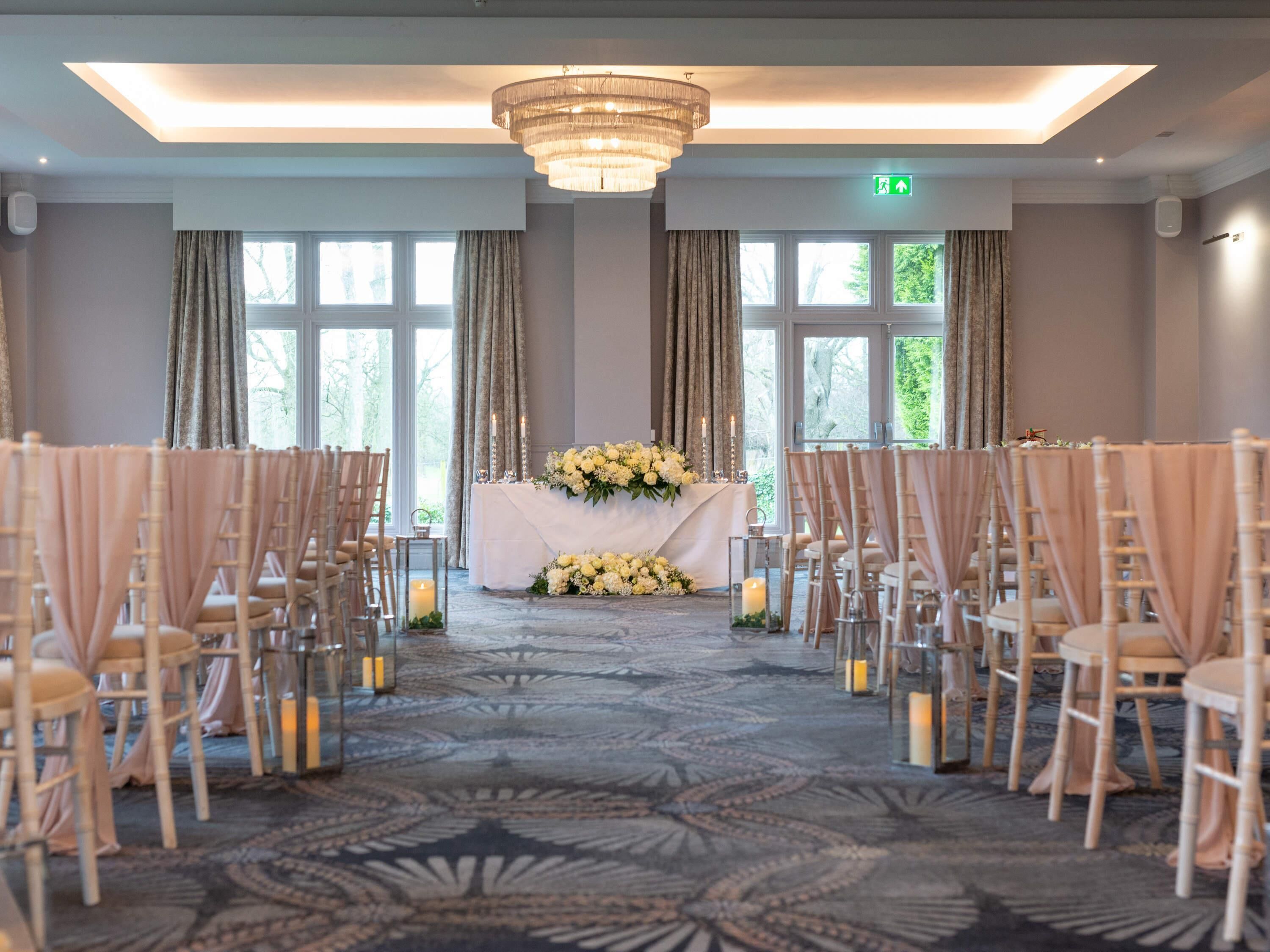 A wedding ceremony setup with rows of chairs, a floral altar, and candles.