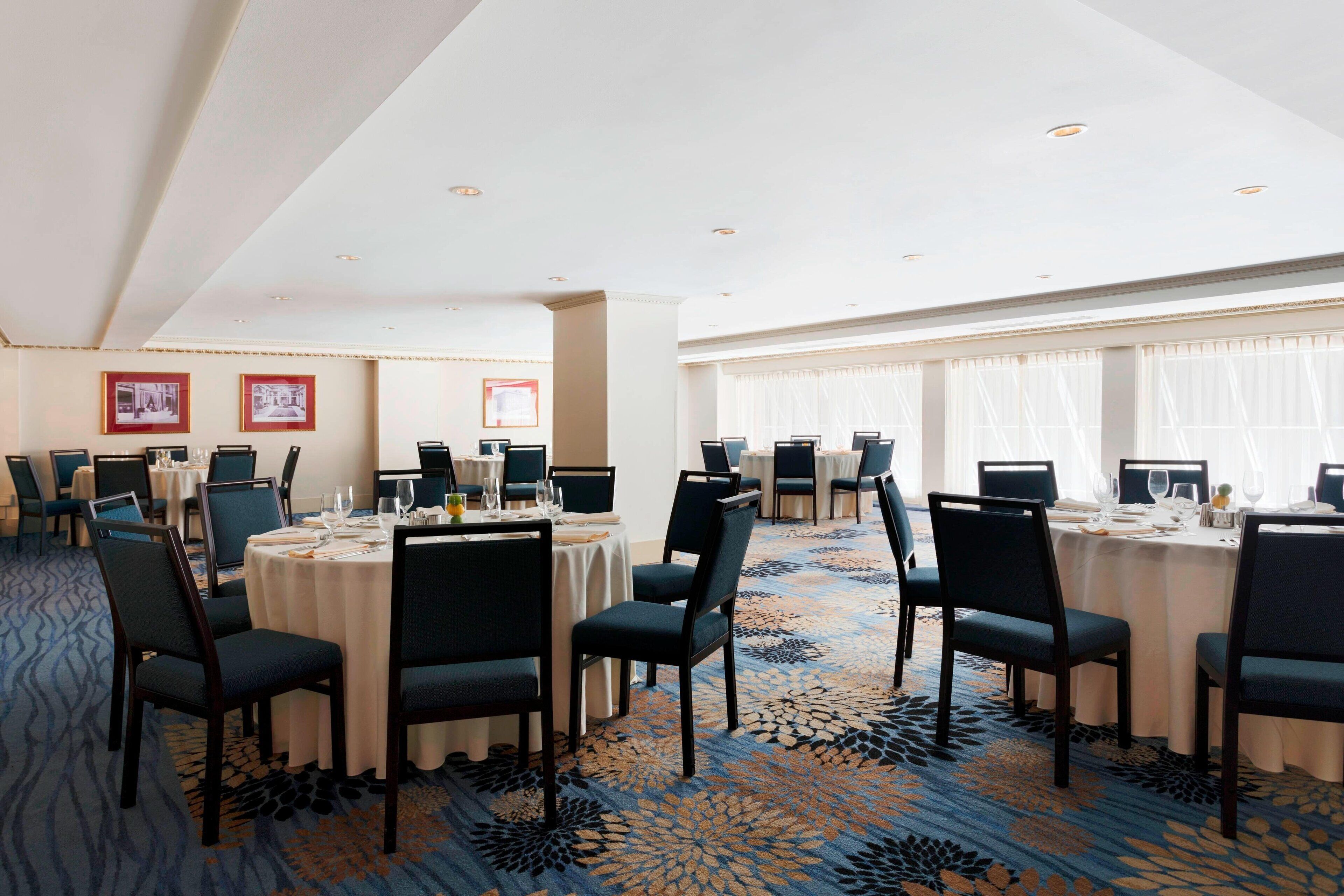 A conference room with round tables, chairs, and framed pictures on the walls.