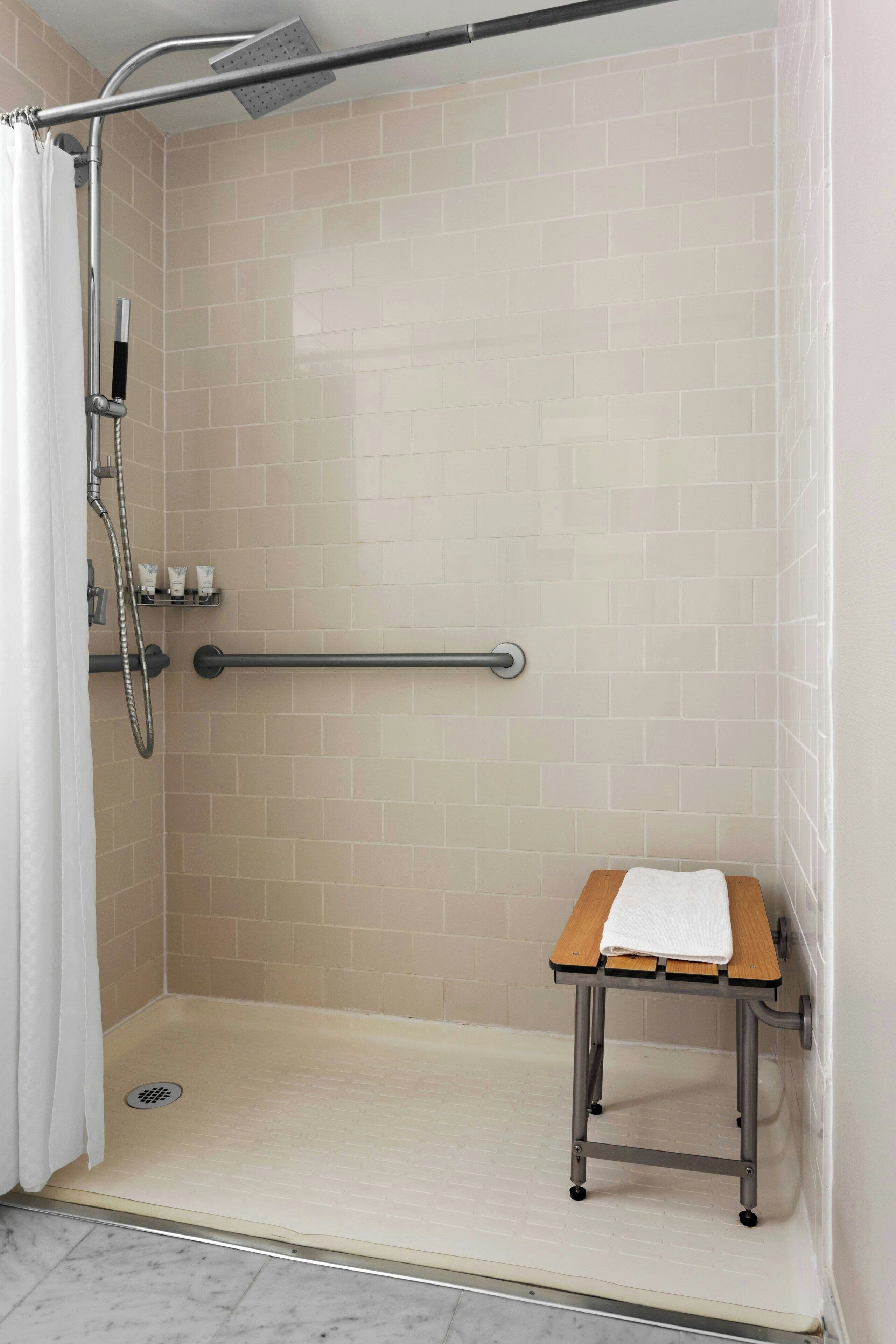 A shower area with a grab bar, a bench, and a towel rack.