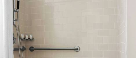 A shower area with a grab bar, a bench, and a towel rack.