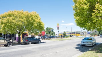Straatbeeld met geparkeerde auto's, een McDonald's bord en een winkel van Jane's T-shirts.
