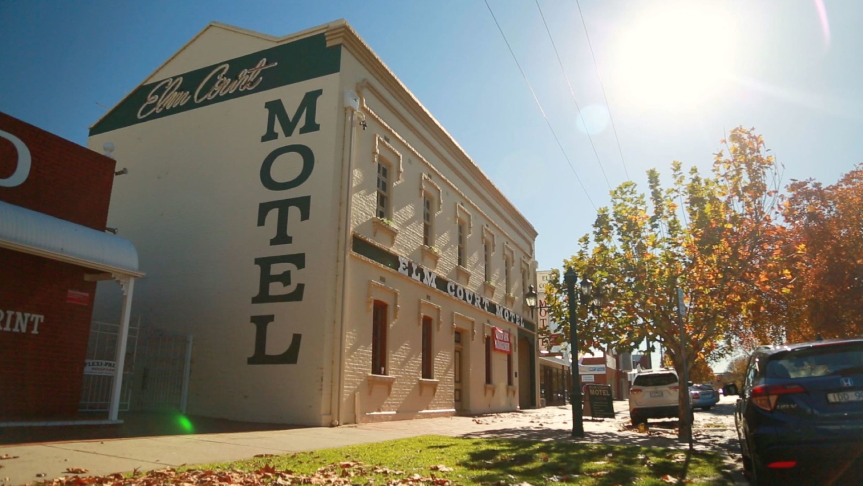Een motel met twee verdiepingen en een opvallend bord met de tekst 'MOTEL' aan de zijkant.