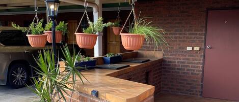 A brick reception area with hanging planters and a car parked in the background.