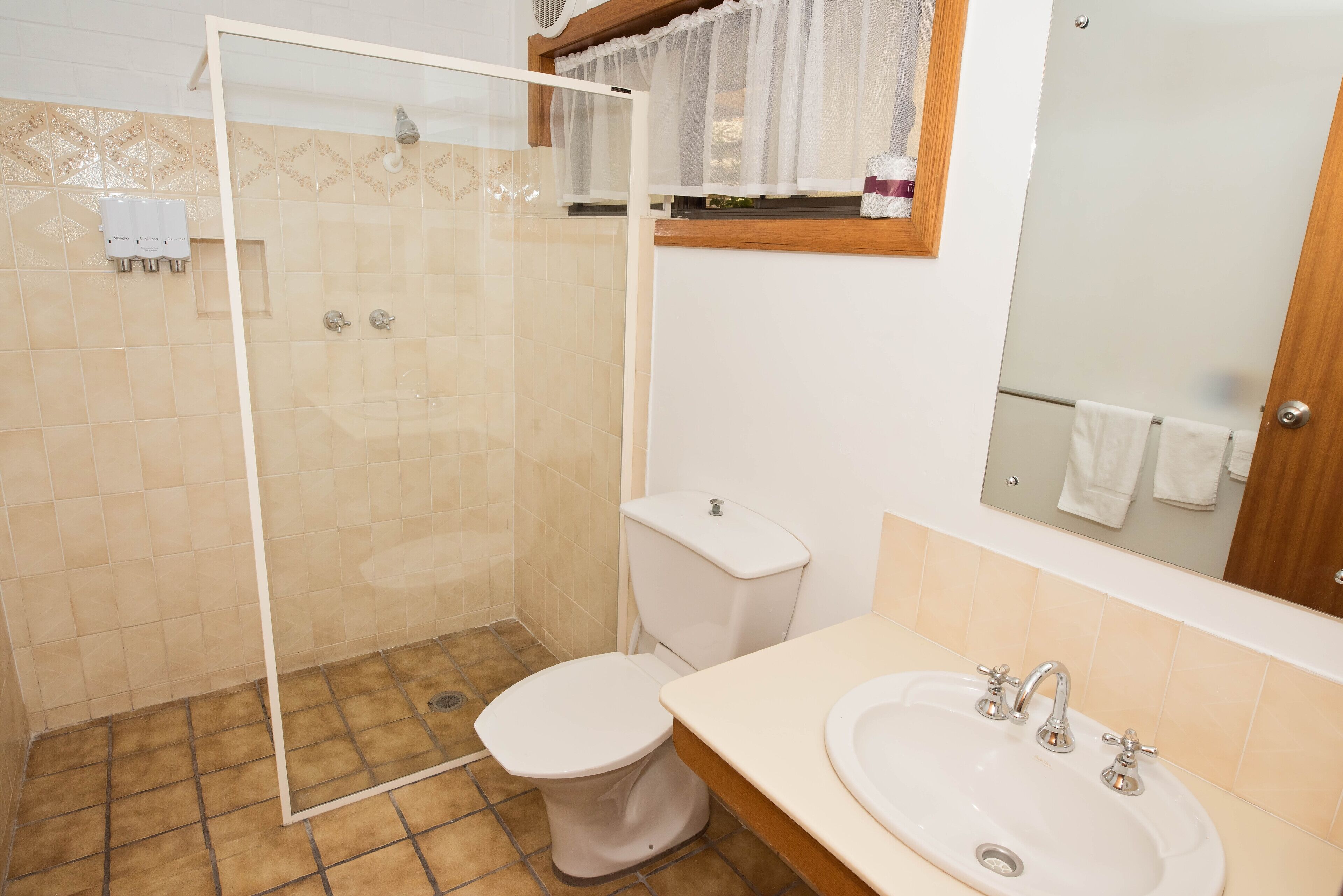 Een badkamer met een douche met glazen wand, een toilet en een wastafel met spiegel erboven.