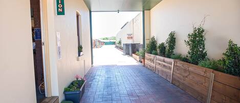 Zona de recepción con un letrero, un banco y un camino que lleva a la entrada.