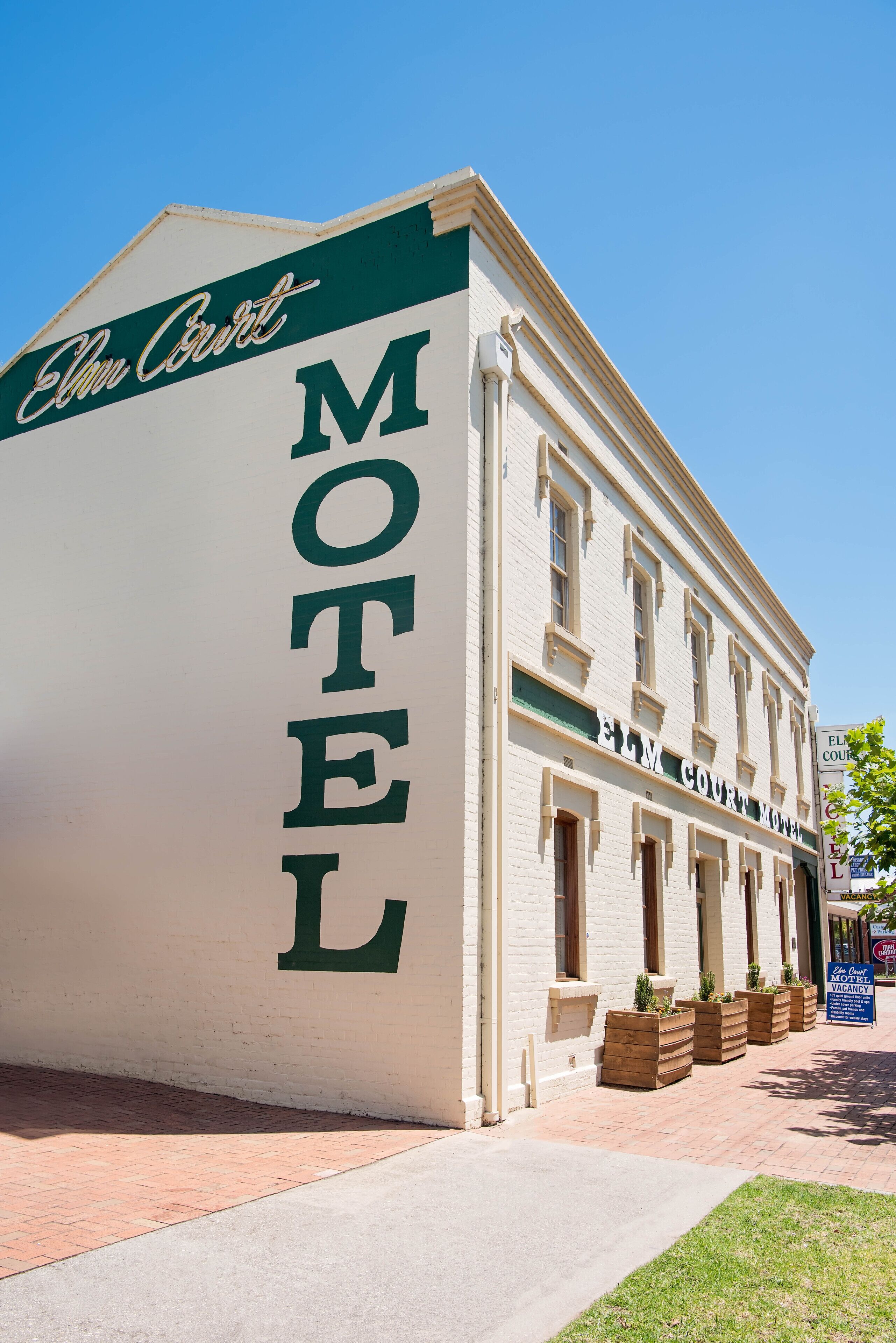 A white building with a green awning and the word "MOTEL" on the side.