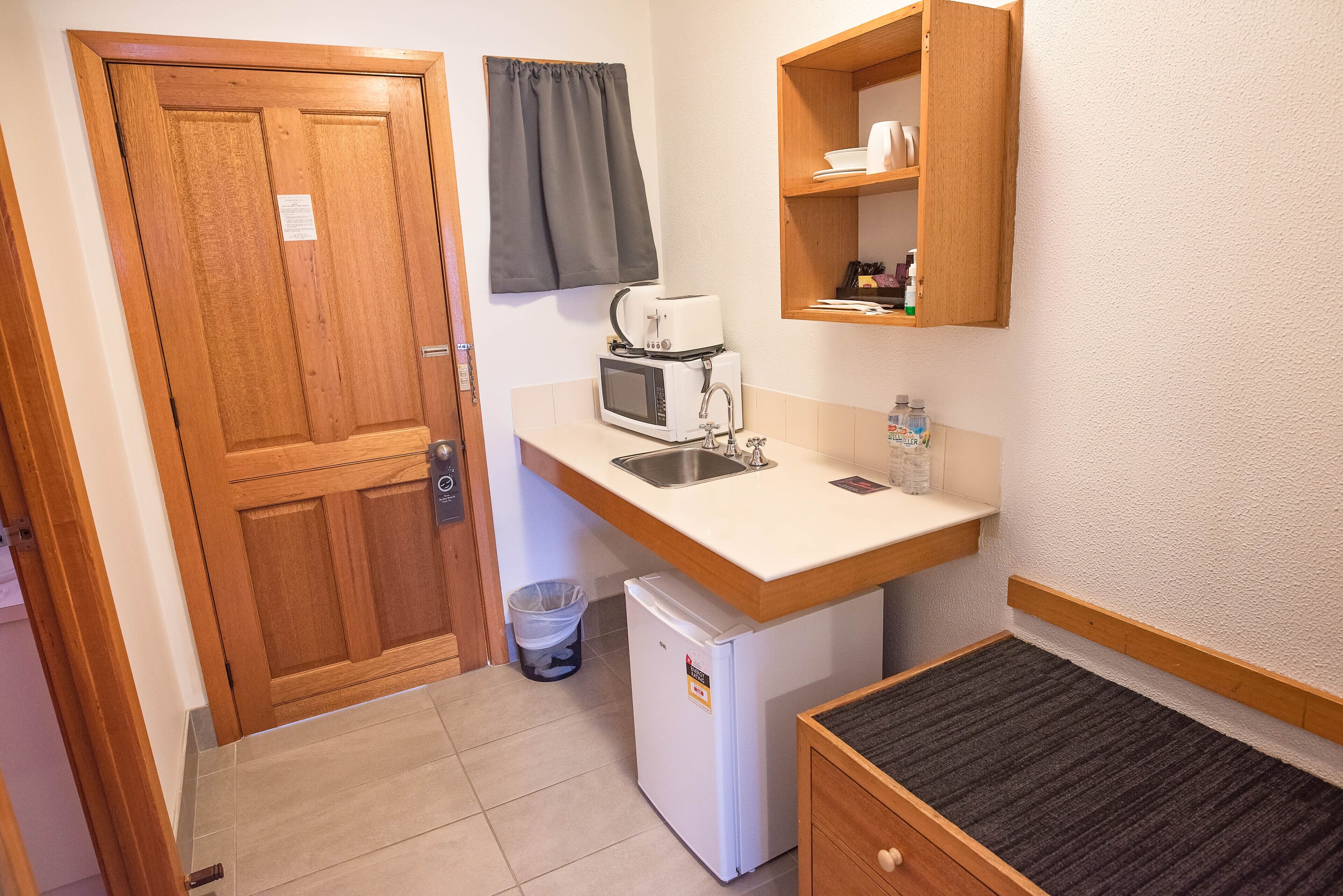 Uma kitchenette compacta com micro-ondas, torradeira e pia.
