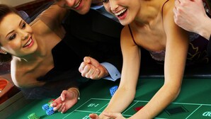 Ein Craps-Tisch mit Würfeln und Jetons, ein Roulette-Rad und ein Blackjack-Tisch.