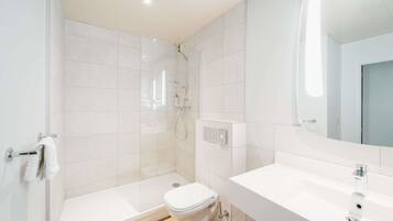 A modern bathroom with a shower, toilet, and sink.