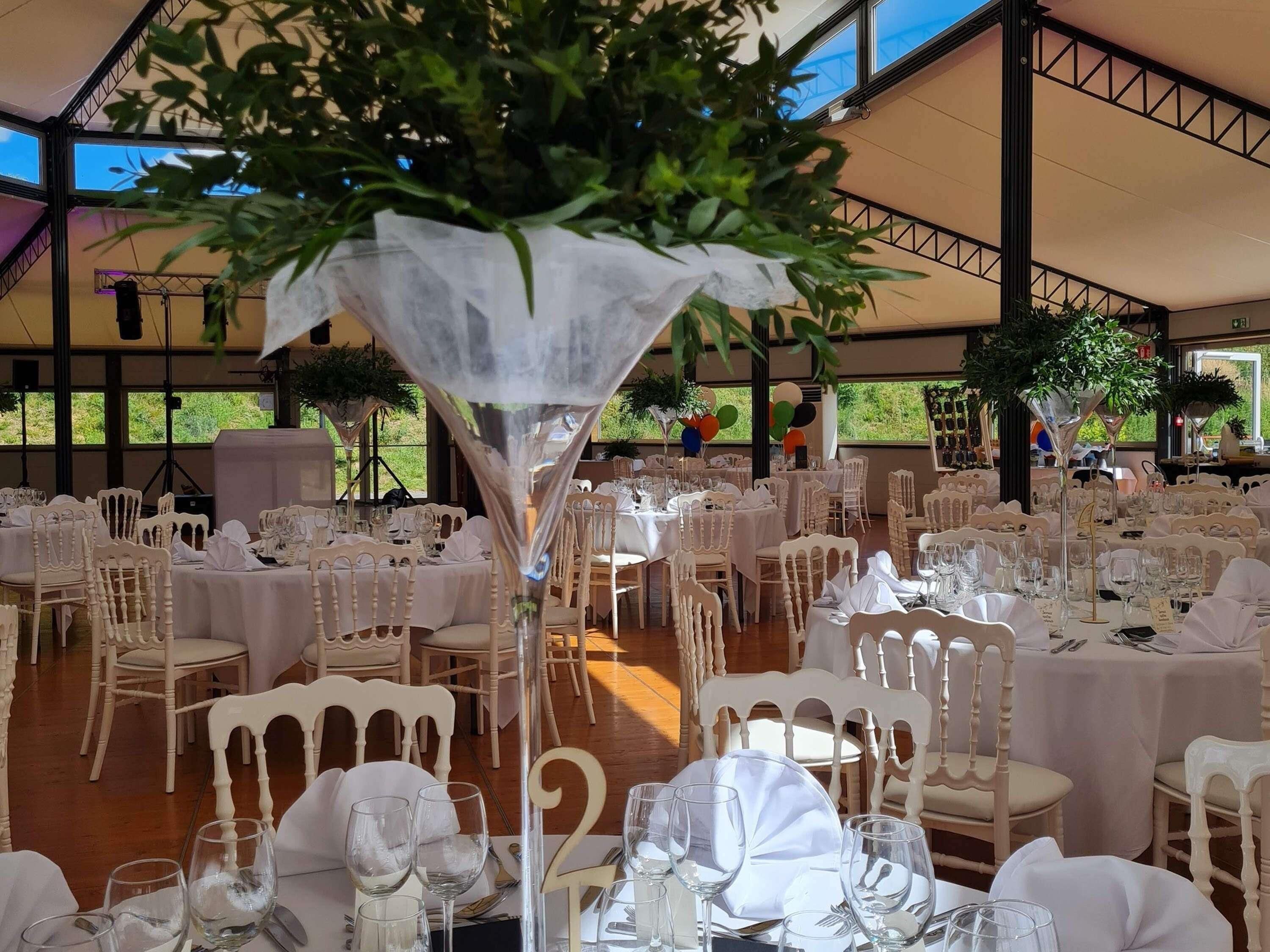 A banquet hall with round tables, white chairs, and a large decorative centerpiece.