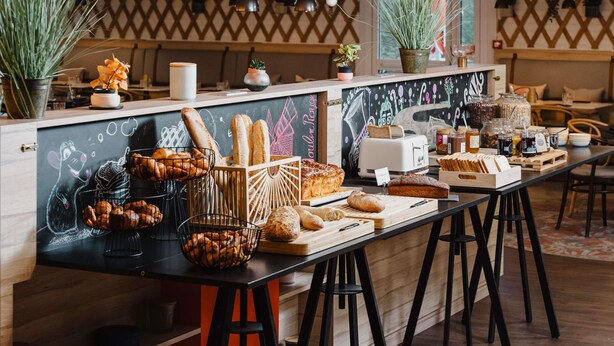 A bakery counter with various breads, pastries, and jars of spreads. - Mercure Lille Aeroport (Lesquin)