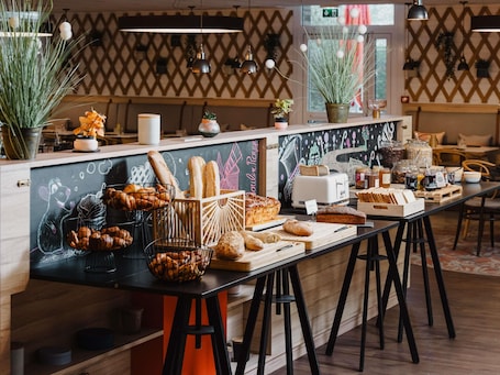 Un comptoir de boulangerie où l’on trouve une variété de pains, de pâtisseries et des pots de confitures et de pâtes à tartiner.. Mercure Lille Aeroport