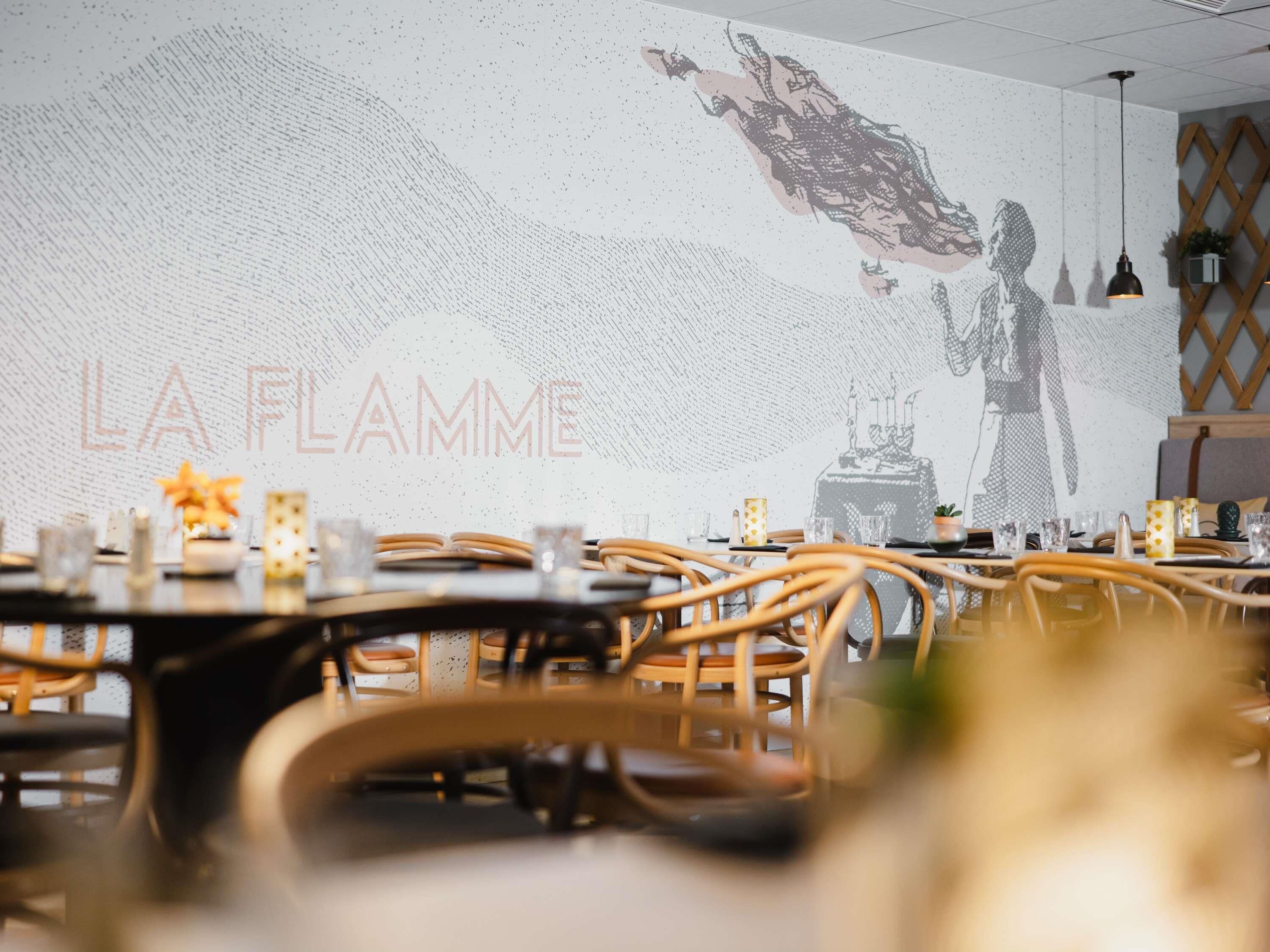 A restaurant interior with tables, chairs, and a wall mural.