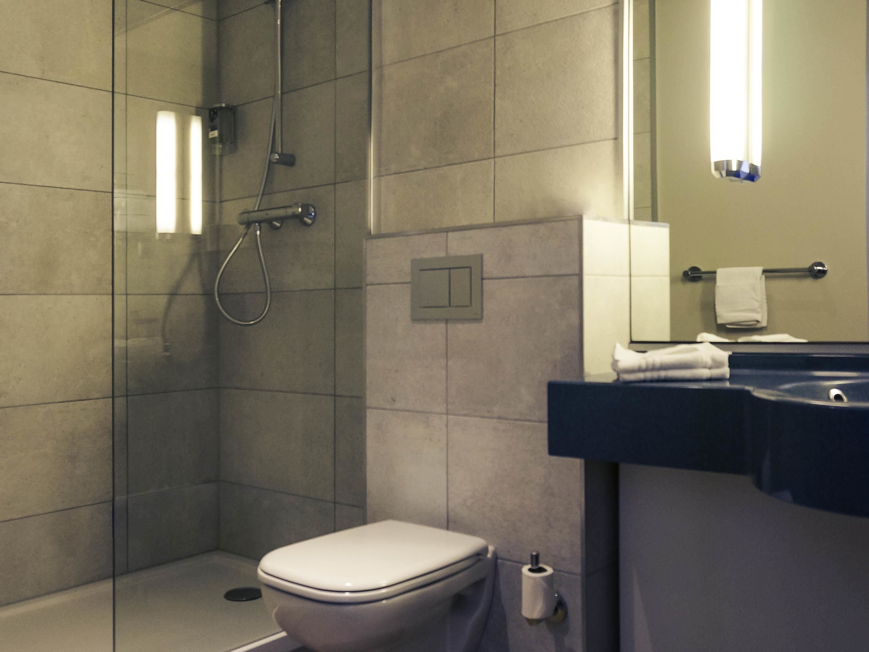A modern bathroom with a glass-enclosed shower, a white toilet, and a sink with a towel rack.