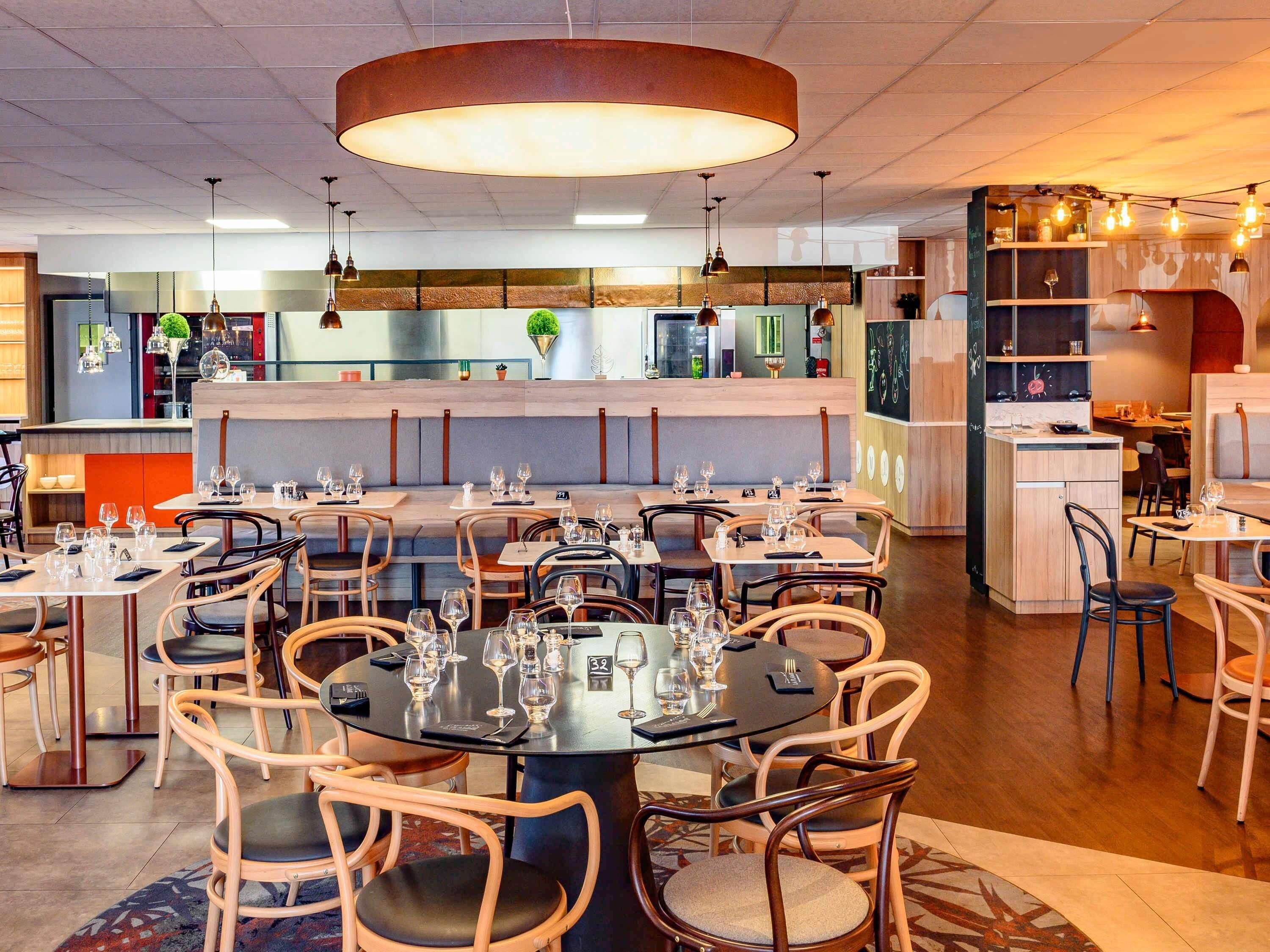 Een restaurant met ronde tafels, stoelen en een bar in het midden.