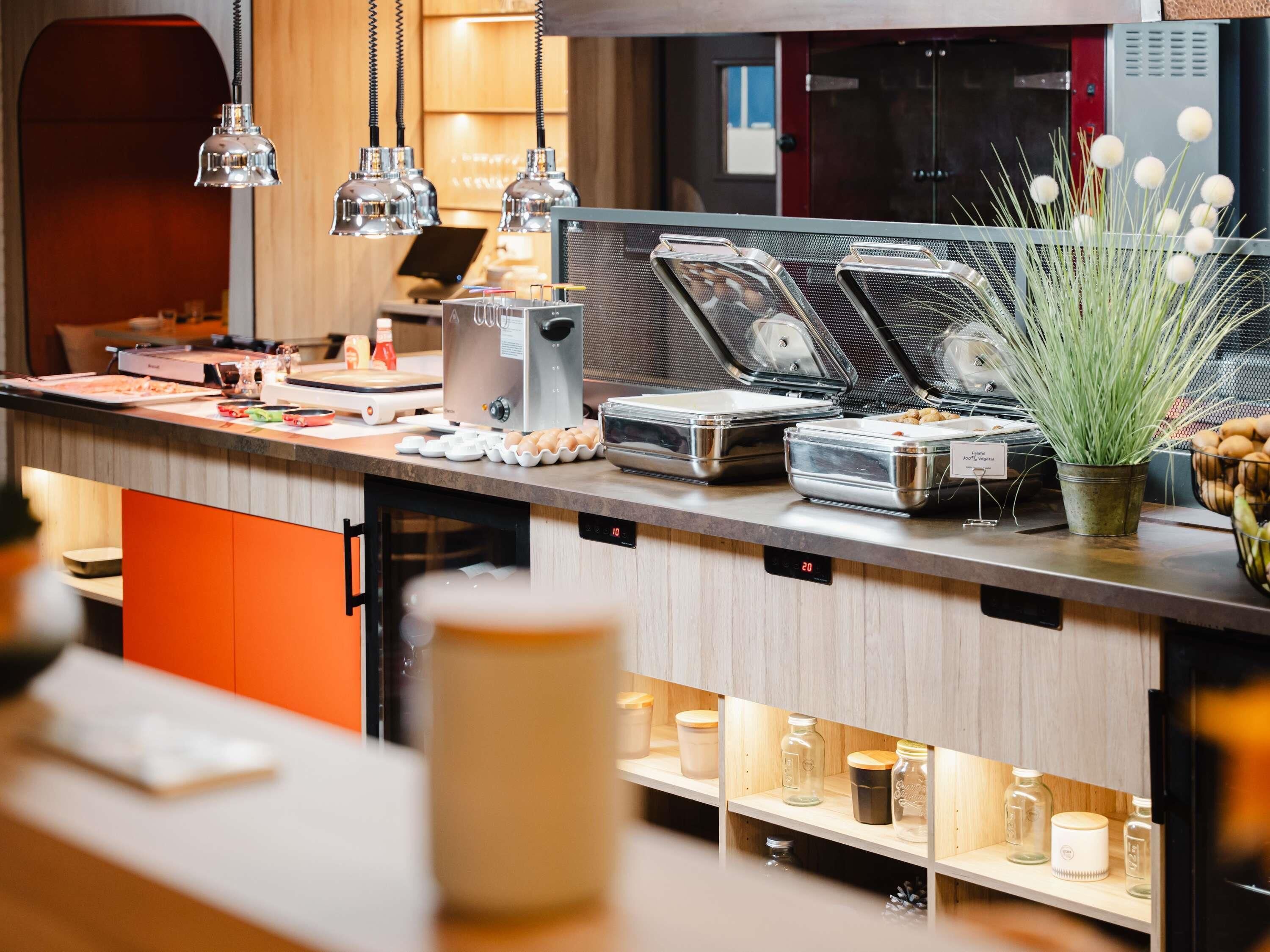 Een moderne keuken met een ingebouwde koffieapparaat, een vitrine voor etenswaren en een potplant.
