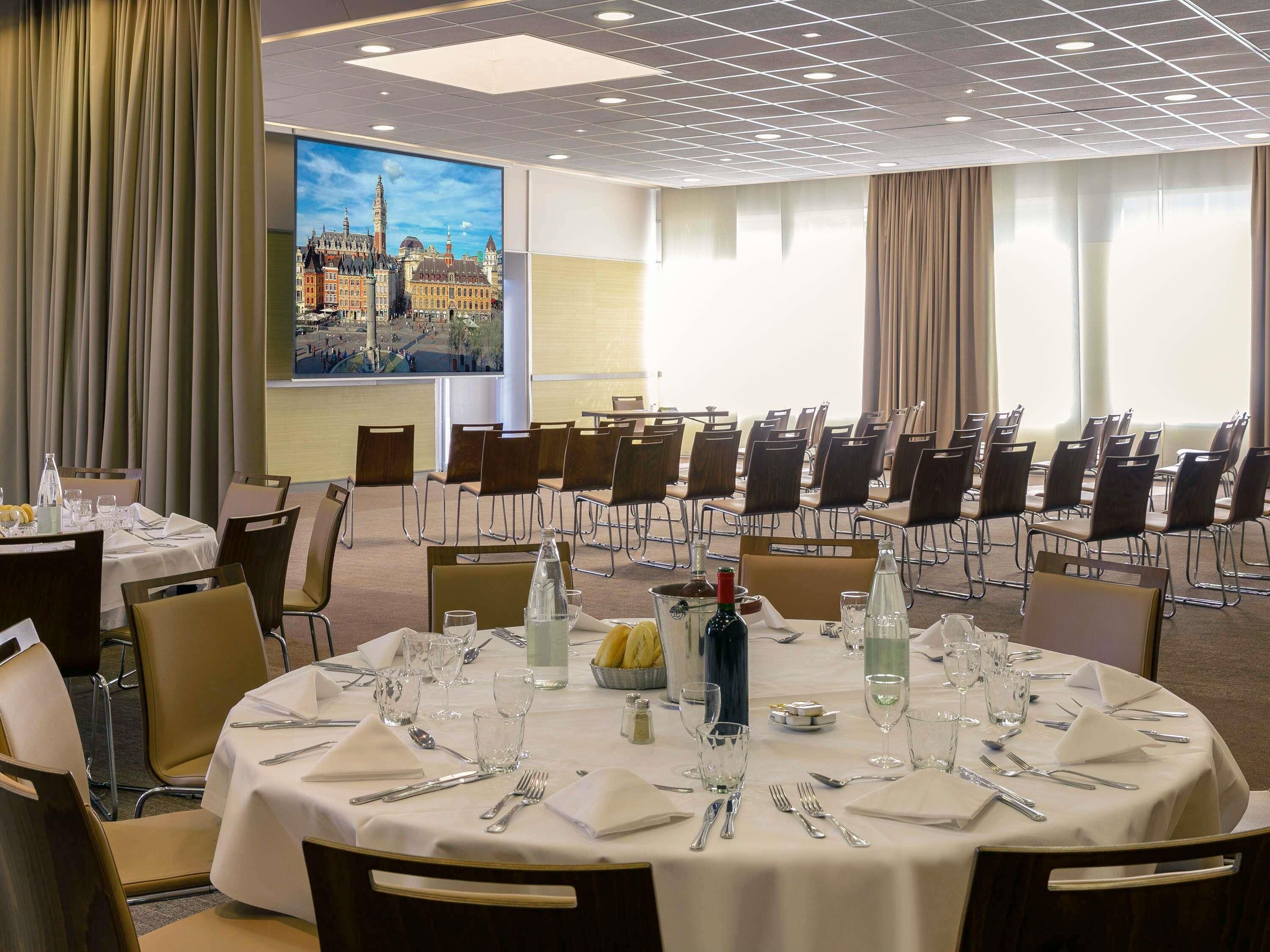 A conference room with round tables, chairs, and a large window with a cityscape view.