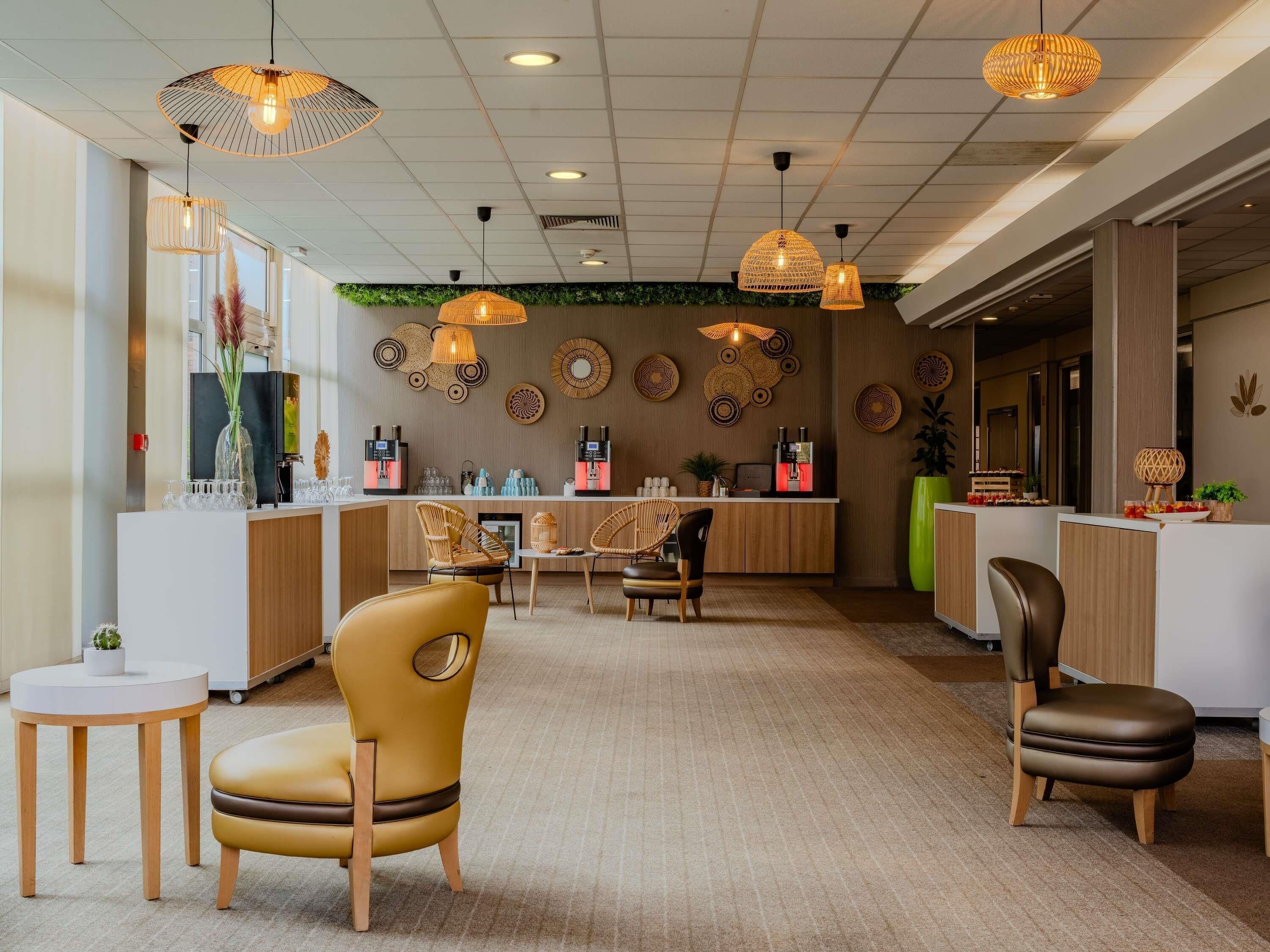 A modern hotel lobby with a reception desk, seating area, and decorative wall art.
