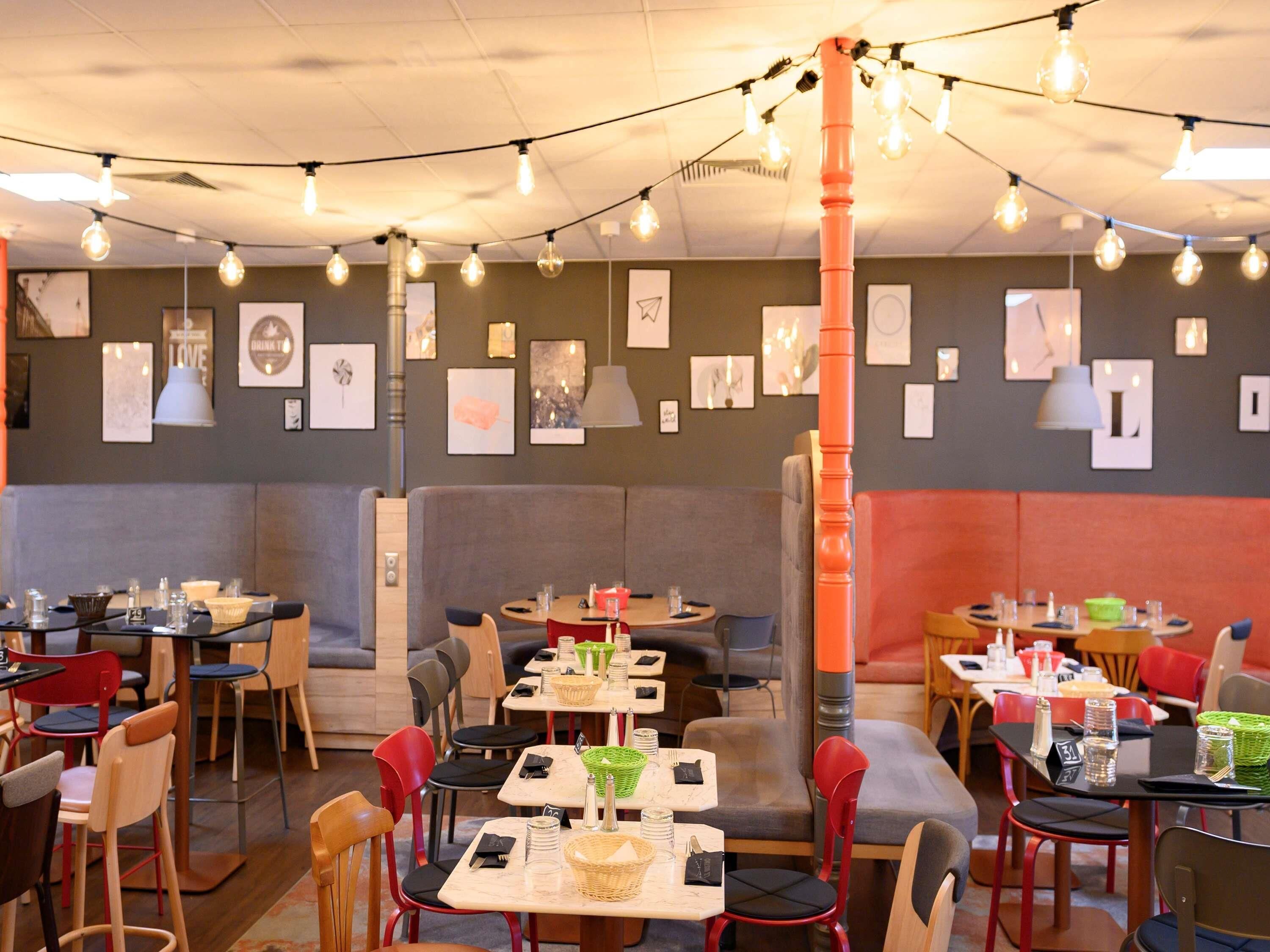 Un restaurant avec des banquettes et des tables, des guirlandes lumineuses et des œuvres d’art encadrées accrochées aux murs.