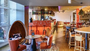 A modern bar area with a variety of seating options, including a unique round table and multiple bar stools. - Mercure Lille Aeroport (Lesquin)