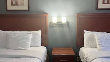 Een hotelkamer met twee bedden, een nachtkastje en wandlampen.